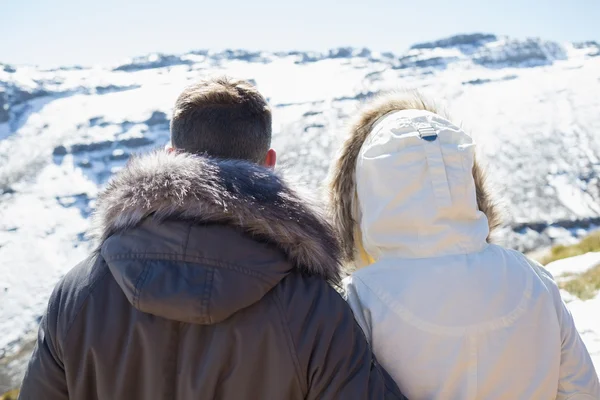 Couple in jackets looking at snowed mountain range — Stock Photo, Image