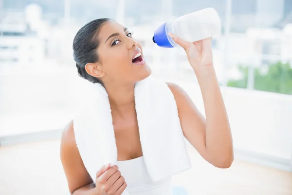 Calm toned brunette with towel holding sports bottle — Stock Photo, Image