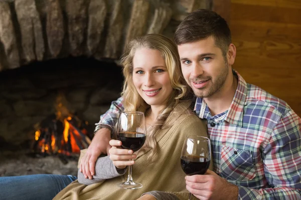 Couple with wineglasses in front of lit fireplace — Stok fotoğraf