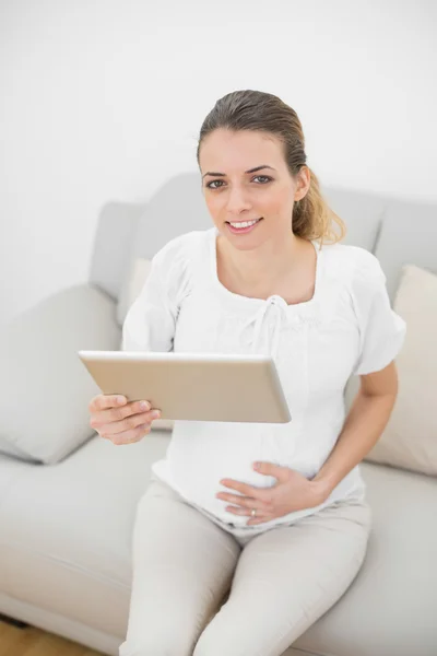 Gravid kvinna med hennes tablett som ler mot kameran — Stockfoto