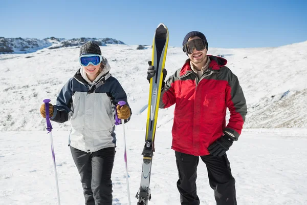 Retrato de una pareja sonriente con equipo de esquí en la nieve — Foto de Stock