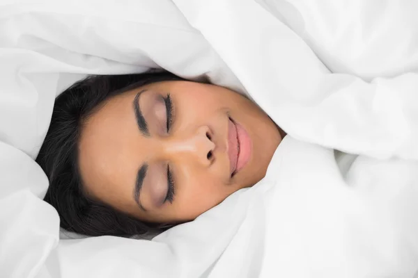 Lovely smiling woman lying on bed under cover — Stock Photo, Image