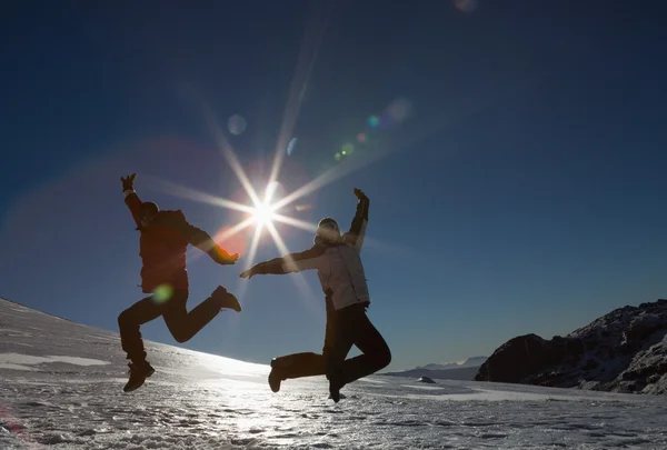 Силует пара стрибки на снігу проти сонця і синього неба — стокове фото