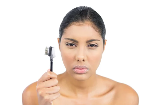 Frowning nude brunette holding eyebrow brush — Stock Photo, Image