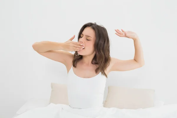 Mujer bostezando mientras se estira en la cama —  Fotos de Stock