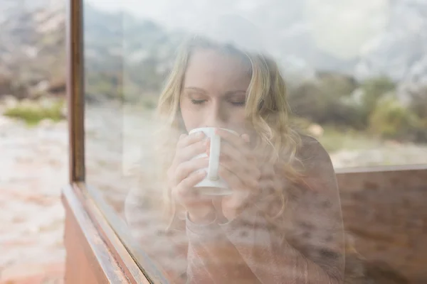 Woman drinking coffee through cabin window — Stock Photo, Image
