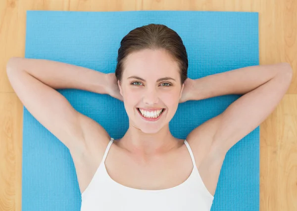 Mujer sonriente acostada en una alfombra de ejercicio — Foto de Stock