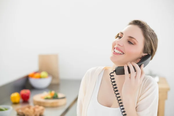 Mooie vrouw bellen met een telefoon in haar keuken lachen — Stockfoto