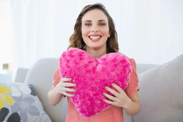 Cheerful pregnant woman holding pink heart pillow — Stock Photo, Image