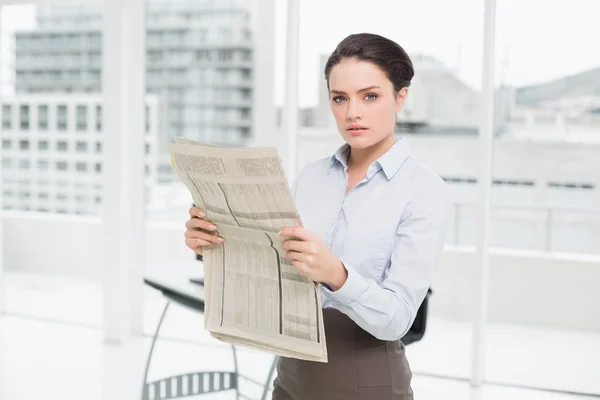Ernstige jonge zakenvrouw met krant in office — Stockfoto