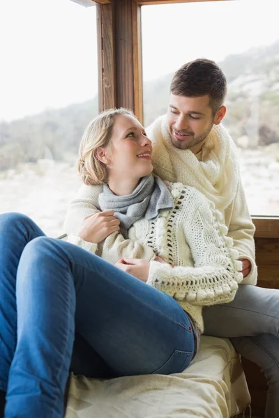 Loving couple in winter clothing sitting in cabin — Stock Photo, Image