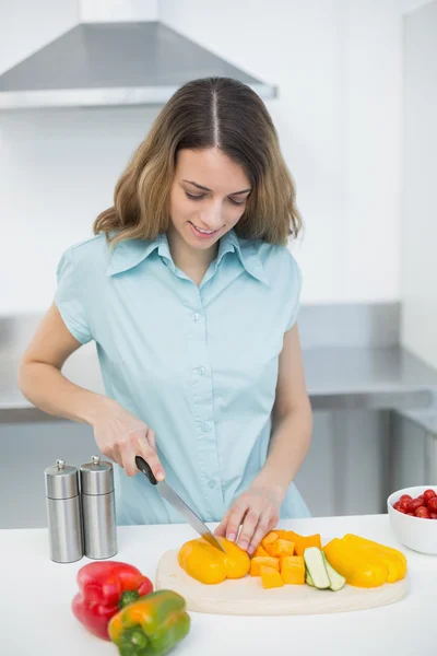 Tranquillo bruna donna taglio verdura in piedi nella sua cucina — Foto Stock