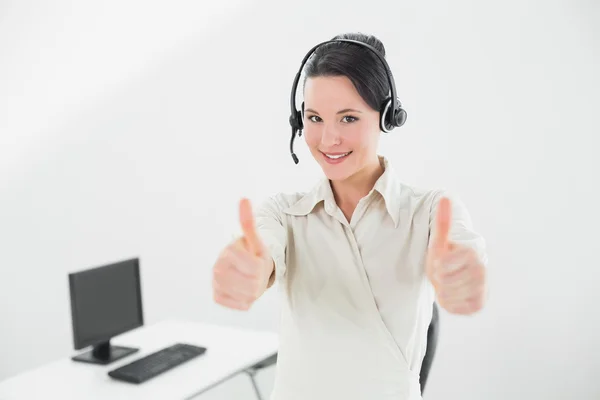 Businesswoman wearing headset and gesturing thumbs up in office — Stock Photo, Image