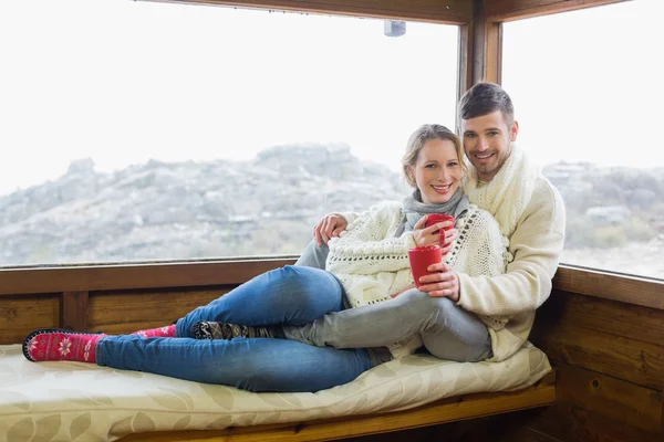 Casal em desgaste de inverno com xícaras de café contra a janela da cabine — Fotografia de Stock