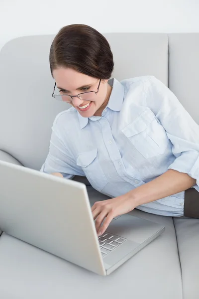 Netjes geklede vrouw met behulp van laptop op sofa — Stockfoto