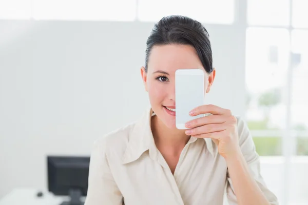 Femme d'affaires tenant son téléphone portable à l'œil — Photo