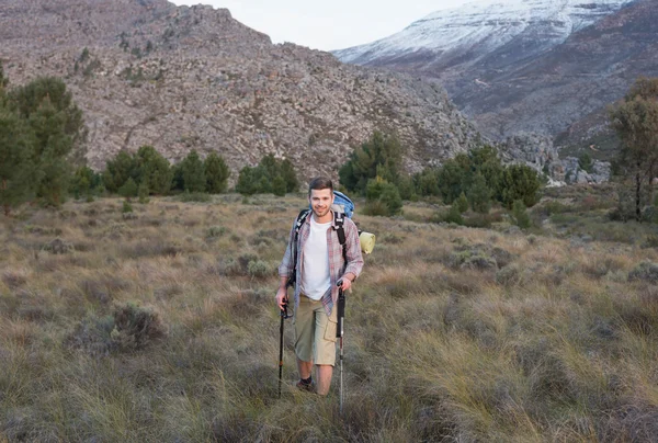 Hombre con mochila y bastones de trekking en el paisaje forestal — Foto de Stock