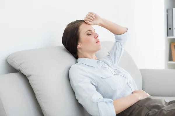 Serious well dressed woman sitting on sofa — Stock Photo, Image