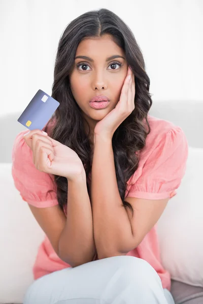 Šokoval, roztomilá brunetka sedí na gauči, ukazují kreditních karet — Stock fotografie