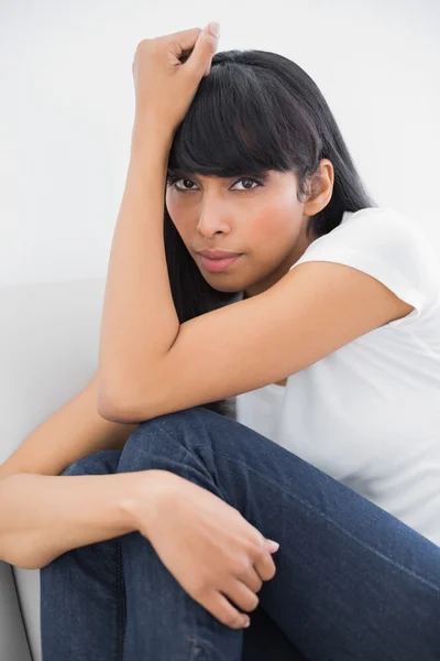 Hermosa mujer pensante sentada en el sofá en la sala de estar brillante — Foto de Stock