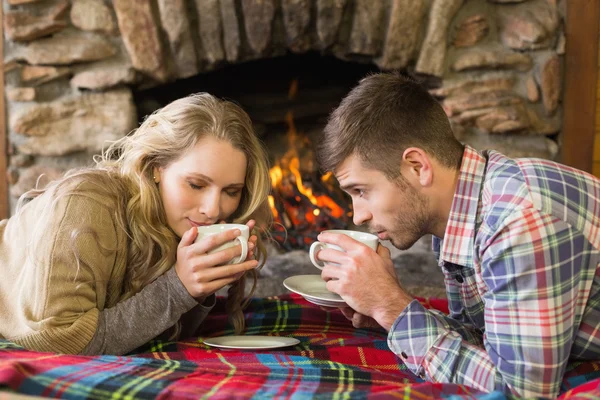 Pareja romántica bebiendo té frente a la chimenea encendida — Foto de Stock