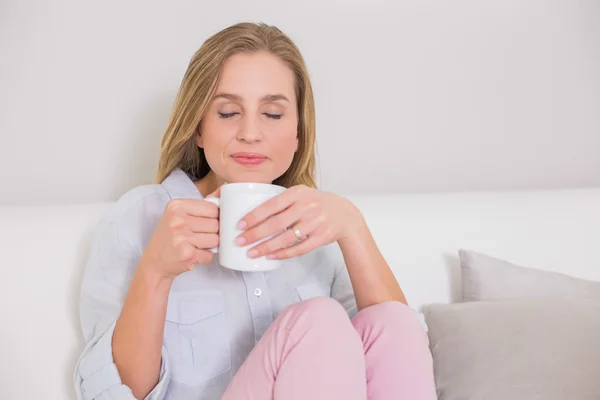 Peaceful casual blonde sitting on couch holding mug — Stock Photo, Image