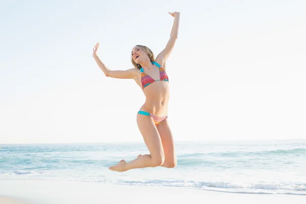 Beautiful blonde young woman jumping on beach — Stock Photo, Image