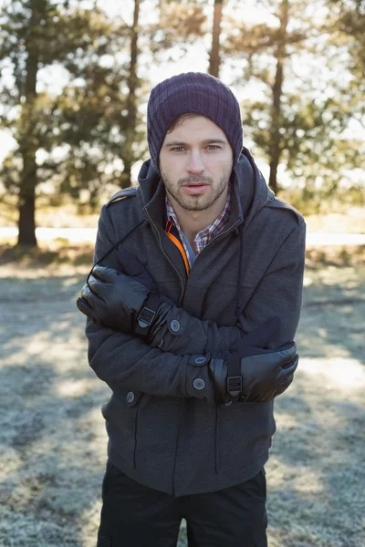 Man in warm clothing shivering while having a walk in forest — Stock Photo, Image