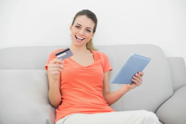 Aantrekkelijke geamuseerd vrouw thuis winkelen met haar tablet — Stockfoto