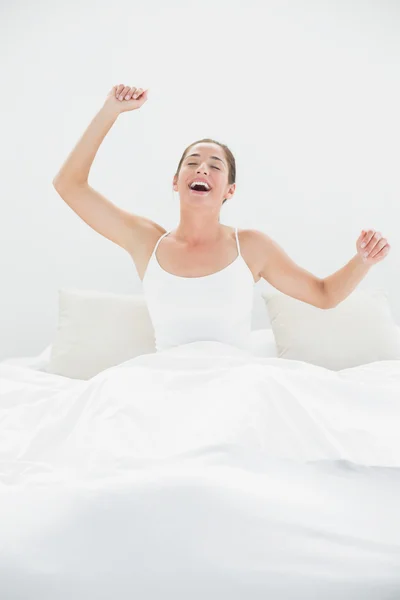 Mulher alegre bocejando enquanto estirando os braços na cama — Fotografia de Stock