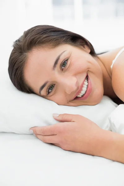 Lächelnde junge Frau, die im Bett liegt — Stockfoto