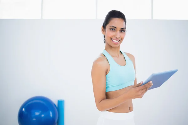 Leuke slanke vrouw bezig met haar tablet staande in fitness zaal — Stockfoto