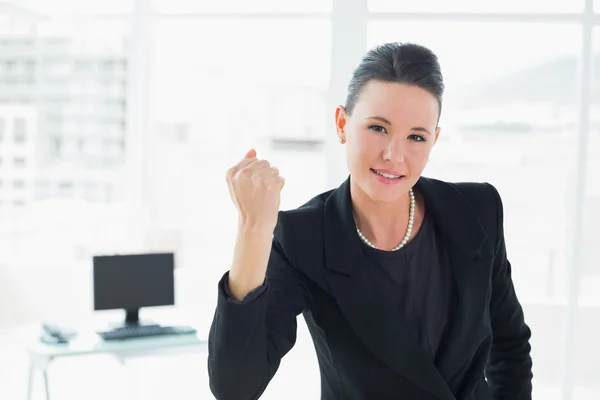 Elegant businesswoman clenching fist in office — Stock Photo, Image
