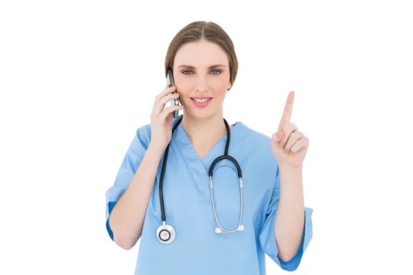 Mulher bonita médico telefonando e apontando com o dedo — Fotografia de Stock