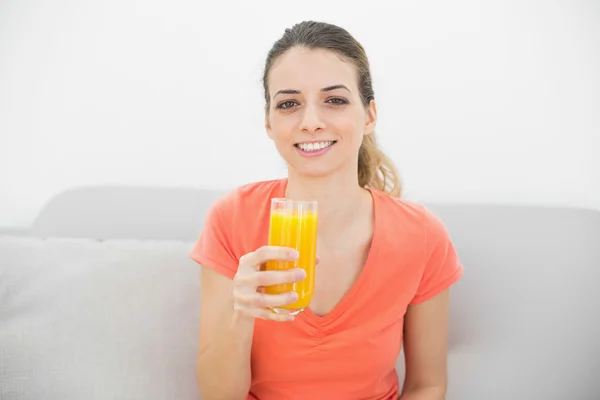 Beautiful calm woman smiling at camera holding a glass of orange — Stock Photo, Image
