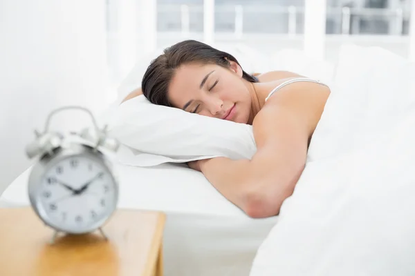 Schlafende Frau mit verschwommenem Wecker auf Nachttisch — Stockfoto