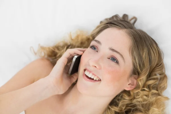Ziemlich glückliche Blondine liegt im Bett und telefoniert mit Handy — Stockfoto