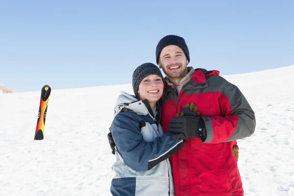 Happy loving couple with ski board on snow in background