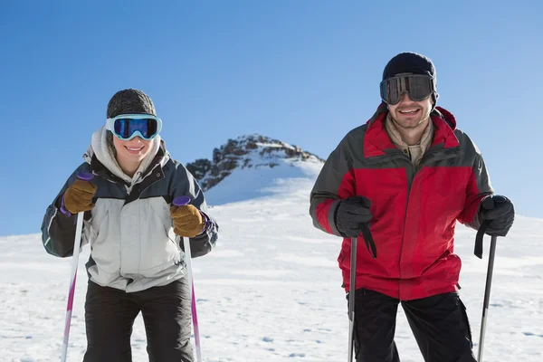 Portret van een glimlachende paar met skistokken op sneeuw — Stockfoto