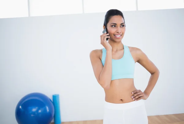 Belle femme souriante posant avec la main sur la hanche tout en téléphonant — Photo