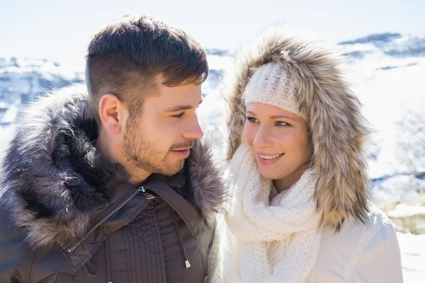 Couple in fur hood jackets against snowed mountain — Stock Photo, Image