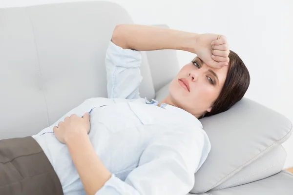 Serious well dressed woman lying on sofa — Stock Photo, Image