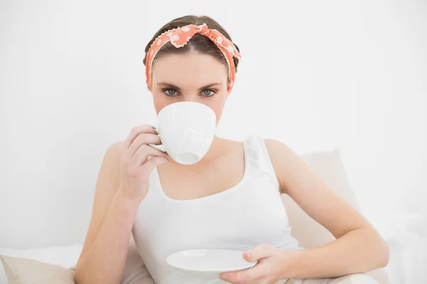 Woman drinking a cup of tea looking into the camera — Stock Photo, Image
