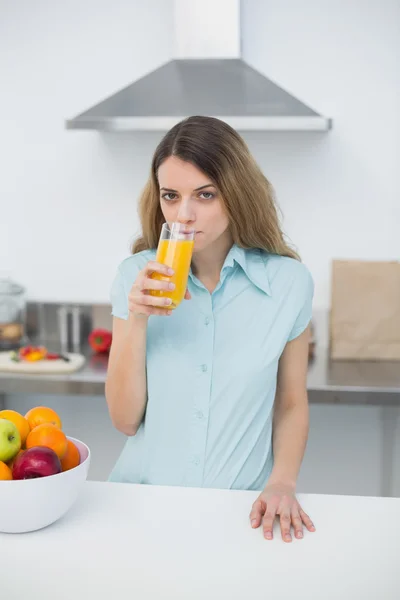 Giovane donna seria che beve un bicchiere di succo d'arancia — Foto Stock