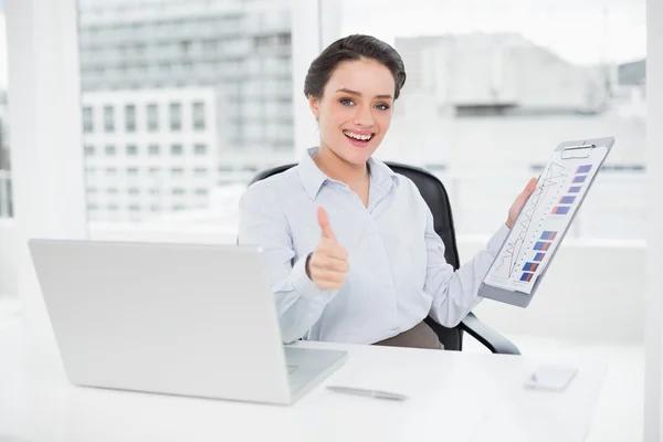 Mujer de negocios con gráficos y portátil gesto pulgares hacia arriba en offi — Foto de Stock