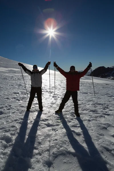 剪影夫妇与滑雪杖在雪上举手 — 图库照片