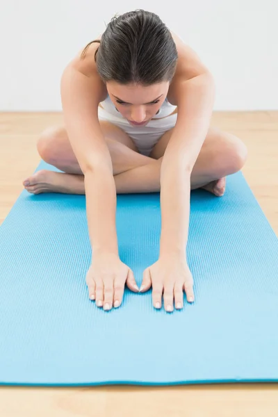 Sporty woman stretching hands on exercise mat — Stock Photo, Image