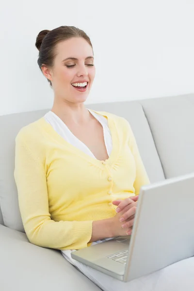 Mujer alegre casual utilizando el ordenador portátil en el sofá —  Fotos de Stock