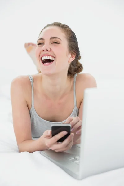 Mulher casual alegre usando celular e laptop — Fotografia de Stock
