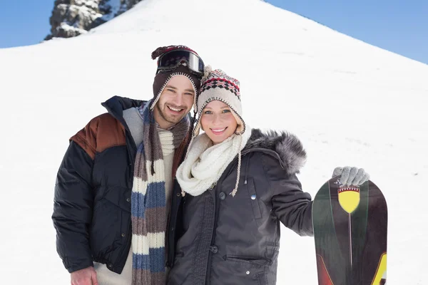 Portrait of a smiling couple in jackets with ski board — Stock Photo, Image